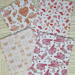 Könnte beinhalten: Vier Blätter Papier mit Western-Motiven. Designs umfassen Cowboy-Stiefel, Hüte, Kakteen, Hufeisen und Schleifen in Rosa-, Pfirsich- und Brauntönen. Das Wort "Howdy" steht auf einem Blatt.
