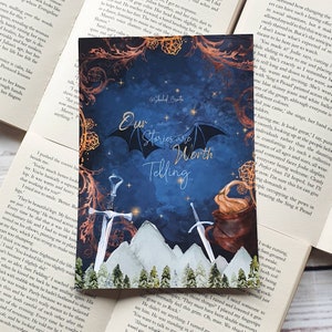 以下が含まれることがあります： 星、山、木のある濃い青色の空の水彩画。2本の剣が山脈の前に交差している。蓋のある大釜が画像の右側にある。「私たちの物語は語る価値がある。」というテキストが画像の中央にある。