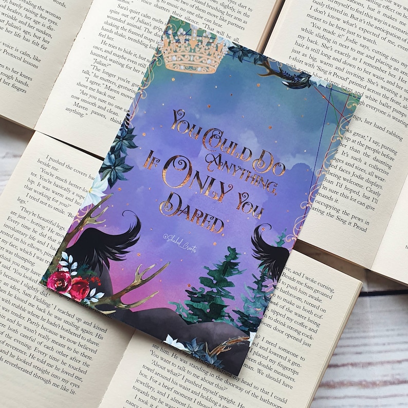 May include: A purple and gold foil print with a quote from the book "Throne of Glass" by Sarah J. Maas. The quote reads "You could do anything, if only you dared." The print features a black raven with a crown and a forest background.