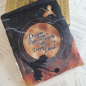 May include: A black book cover with a gold circle design featuring a dragon and the text "A Dragon Without Its Rider Is A Tragedy. A Rider Without Their Dragon Is Dead."
