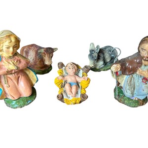 Pode incluir: Um pres&eacute;pio vintage com figuras de Maria, Jos&eacute;, o menino Jesus numa manjedoura, um burro e uma vaca. As figuras s&atilde;o pintadas com cores suaves e t&ecirc;m um aspeto cl&aacute;ssico e envelhecido.