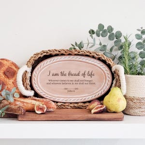 May include: An oval-shaped, light pink ceramic platter with a rope-textured border, featuring the black printed text: I am the bread of life. Whoever comes to me shall not hunger, and whoever believes in me shall not thirst. John 6.