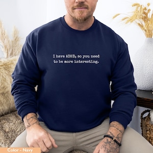 May include: Navy blue sweatshirt with the text "I have ADHD, so you need to be more interesting." printed in white. The sweatshirt is a crew neck style.
