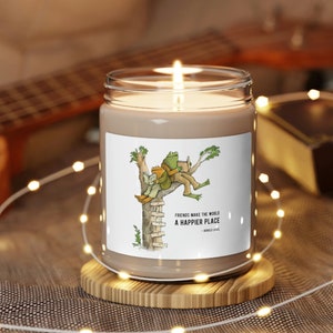 May include: A brown candle with a white label featuring a cartoon illustration of two friends sitting on a tree branch. The label reads "Friends make the world a happier place - Winnie the Pooh".