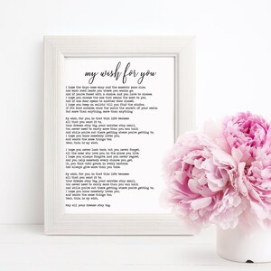 Può includere: Una stampa incorniciata bianca con una poesia intitolata "my wish for you". La poesia è stampata in testo nero su sfondo bianco. La stampa è su una superficie bianca con un mazzo di peonie rosa in una tazza bianca.