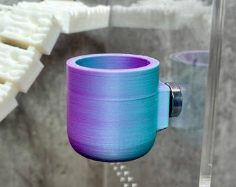 Può includere: Un piccolo bicchiere cilindrico con una finitura sfumata che passa dal viola in alto al blu e al turchese alla base. Il bicchiere presenta un attacco circolare metallico su un lato, che consente di montarlo su una superficie piana e trasparente.