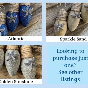 May include: Three light bulb ornaments decorated with glitter and a starfish charm. The ornaments are in three colors: blue, beige, and silver. The ornaments are labeled "Atlantic", "Sparkle Sand", and "Golden Sunshine".