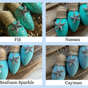 May include: Four teal blue lightbulb ornaments with a burlap bow and a silver starfish on each. The ornaments are labeled "Fiji", "Nassau", "Seafoam Sparkle", and "Cayman".