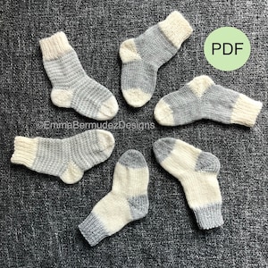 May include: Five pairs of hand-knitted baby socks in a grey and white striped pattern. The socks are laid out in a circle on a grey textured surface. The word "PDF" is written in white on a green circle in the top right corner of the image.