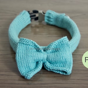 May include: A light blue knitted dog collar with a matching bow tie. The collar has a metal buckle and is designed for small dogs. PDF.