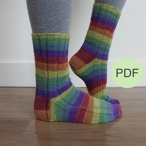 Può includere: Un paio di calzini a righe colorati con uno schema di colori verde, viola, rosso e arancione. I calzini sono lavorati a maglia con una trama a coste. L'immagine include la parola "PDF" in un cerchio verde.