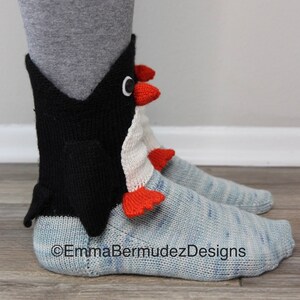 May include: A pair of blue and white knit socks with a black penguin design on the ankle. The penguin has a white belly, red feet and a black beak. The socks are made of a soft, comfortable yarn and are perfect for keeping your feet warm in the winter.