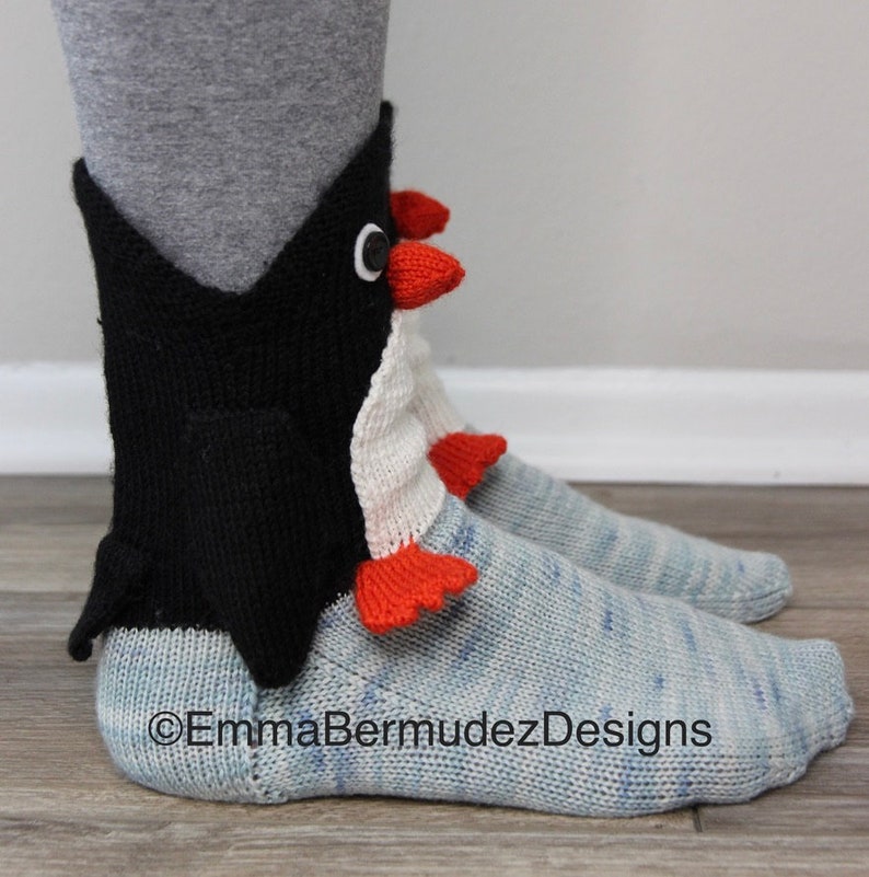 May include: A pair of blue and white knit socks with a black penguin design on the ankle. The penguin has a white belly, red feet and a black beak. The socks are made of a soft, comfortable yarn and are perfect for keeping your feet warm in the winter.