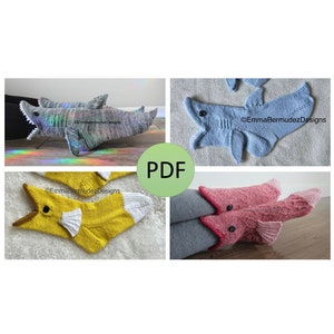 May include: Four pairs of knitted shark socks in different colors: blue, yellow, pink, and gray. The socks are designed to look like sharks with fins and mouths. The image includes the text "PDF" and "EmmaBermudezDesigns".