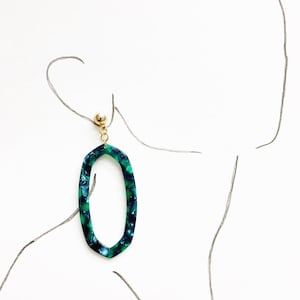 May include: A pair of green and blue oval-shaped earrings with a gold accent. The earrings are made of a marbled material.