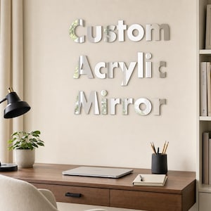 Op de afbeelding: Een set zilverkleurige, reflecterende acrylaatletters bevestigd aan een muur, die de woorden Custom Acrylic Mirror vormen in een vet, schreefloos lettertype. De letters hebben een gladde, glanzende afwerking met een spiegelend effect.