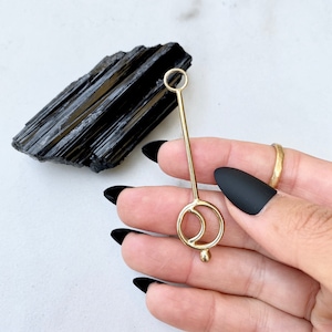 May include: Gold pendant with a circle and crescent moon design. The pendant is on a gold chain.