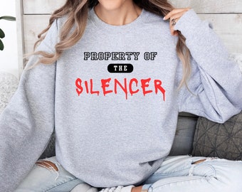Puede incluir: Sudadera gris con el texto "PROPERTY OF THE SILENCER" en negro, con la palabra "SILENCER" en letras rojas que gotean.