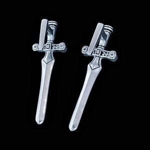 May include: A pair of silver sword earrings with intricate details. The swords have a pointed tip and a cross guard with a star design.