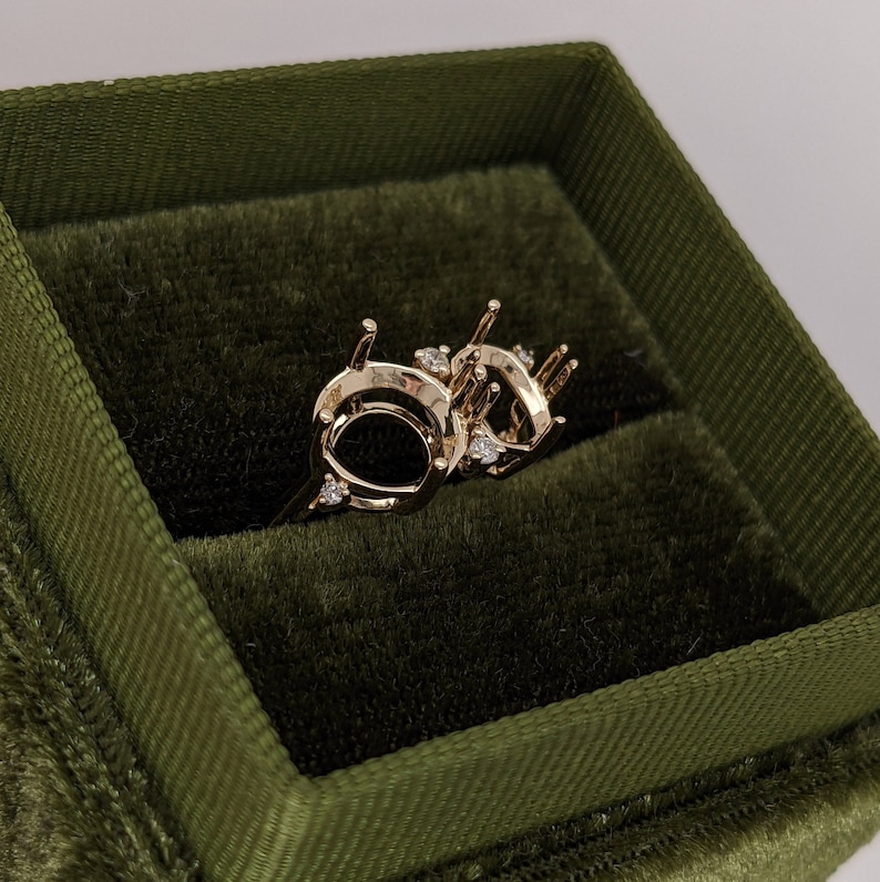 Op de afbeelding: Een gouden ringbezetting met een dubbele ovale vorm en kleine diamanten die in de band zijn gezet.