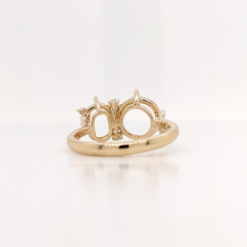 Op de afbeelding: Een gouden ring met twee ovale settings voor edelstenen. De ring is versierd met kleine diamanten.