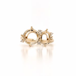 Op de afbeelding: Een gouden ringbezetting met twee open ovale klauwen en een kleinere rechthoekige klauw. De ring is bezet met kleine diamanten.