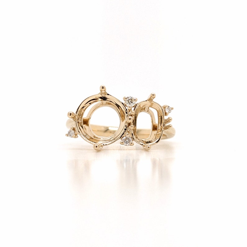 Op de afbeelding: Een gouden ringbezetting met twee open ovale klauwen en een kleinere rechthoekige klauw. De ring is bezet met kleine diamanten.