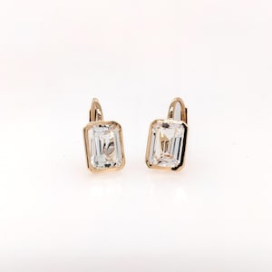 May include: A pair of gold earrings with clear emerald-cut stones.