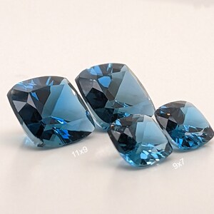 May include: Three blue topaz gemstones of different sizes. The largest measures 11x9, the middle 9x7, and the smallest is not labelled.