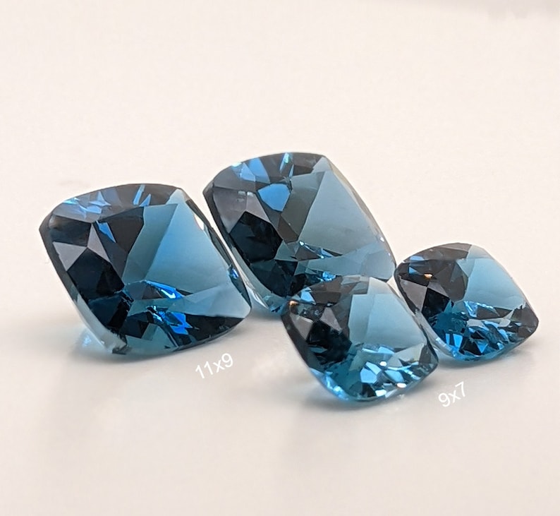 May include: Three blue topaz gemstones of different sizes. The largest measures 11x9, the middle 9x7, and the smallest is not labelled.