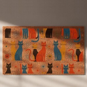 A colorful, patterned door mat with various cat illustrations in different colors and poses.