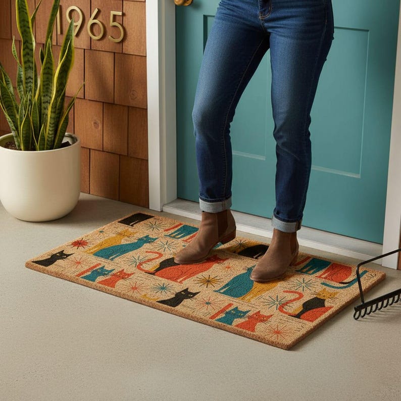 A person standing on a colorful cat-themed doormat in front of a blue door, with a potted plant and a sign displaying the year 1965 nearby.