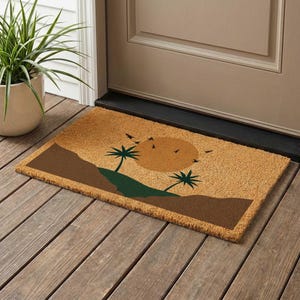 May include: A rectangular doormat with a desert landscape design. The mat features a brown background with a sun, palm trees, and birds in shades of brown, green, and orange. The mat is placed on a wooden porch.