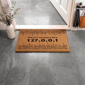 a brown door mat with a black circuit board design and the text "There's no place like 127.0.0.1" printed on it.