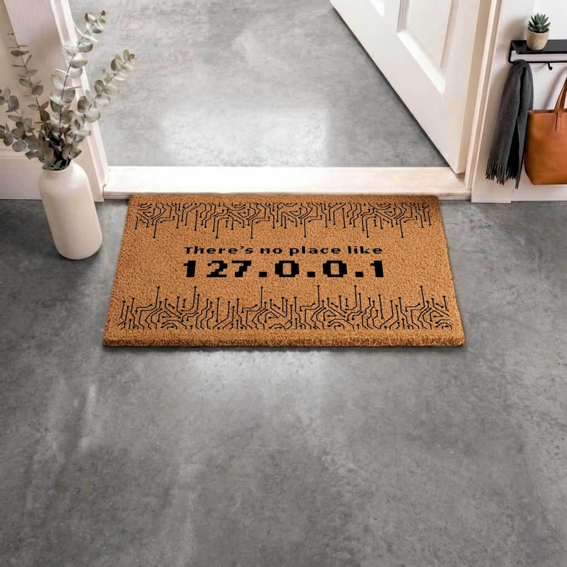 a brown door mat with a black circuit board design and the text "There's no place like 127.0.0.1" printed on it.