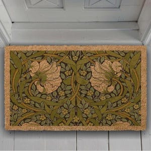 A decorative door mat with a floral pattern in shades of green and brown.