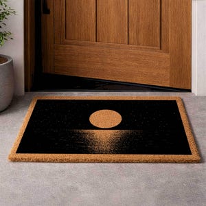 a door mat with a black and orange design depicting a sunset or sunrise.