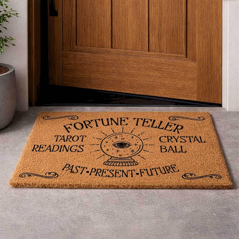 May include: A rectangular doormat with the words "FORTUNE TELLER" and "TAROT READINGS CRYSTAL BALL PAST PRESENT FUTURE" in black. The mat has a crystal ball graphic and is made of a tan, natural fiber material.