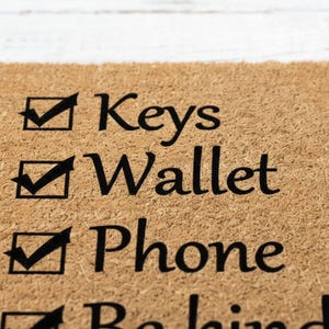 A close-up of a textured surface with a list of items written on it, including 'Keys', 'Wallet', 'Phone', and 'Backpack'.