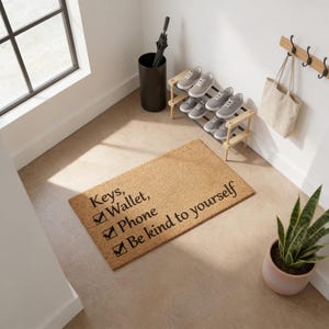 a hallway with a doormat that has a list of items written on it, including keys, wallet, phone, and being kind to oneself.