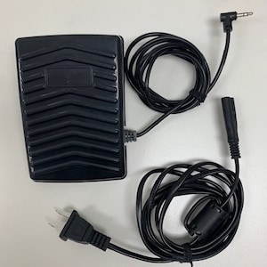 May include: Black foot pedal with a textured surface and a black power cord with a plug. The cord is coiled and has a small black connector on the end.