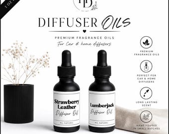 May include: Two 1 oz matte black glass dropper bottles labeled Strawberry Leather and Lumberjack diffuser oils. The bottles feature black dropper caps and white labels. Text includes Haley's Designs, Diffuser Oils, Premium Fragrance Oils, and All Natural.