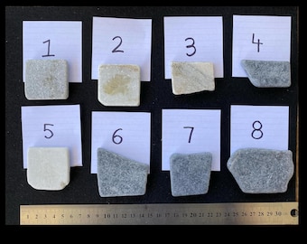 May include: Eight numbered white cards with different grey and white stones on top of them. The cards are arranged in two rows of four. A ruler is visible at the bottom of the image.