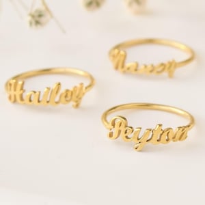 May include: Five gold rings with different names engraved on them: Hailey, Nancy, Susan, Peyton, and Betty.