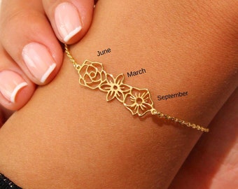Puede incluir: Un brazalete de oro con tres dijes de flores, cada uno representando un mes diferente: junio, marzo y septiembre.