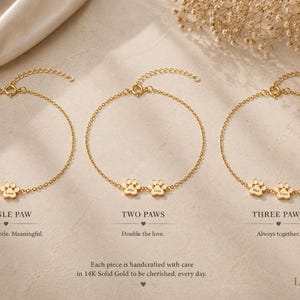 May include: Three gold chain bracelets featuring small paw print charms. The first bracelet has one paw, the second has two, and the third has three. Each charm is engraved with a name. Text labels include SINGLE PAW, TWO PAWS, and THREE PAWS.