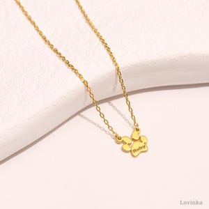 Puede incluir: Collar de cadena dorada con un peque&ntilde;o colgante en forma de huella de pata. La huella de pata tiene el nombre "Ruby" grabado.