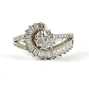 May include: A silver ring with a swirl design and clear cubic zirconia stones.