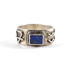May include: A silver ring with a rectangular, deep blue stone at the center. The ring has decorative elements on the band, including a rope-like border around the stone and other geometric designs. The ring is likely made of sterling silver.