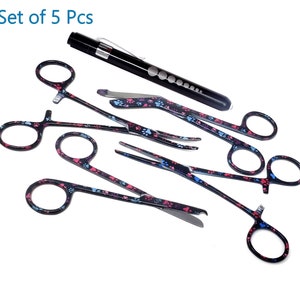 May include: Set of five black stainless steel grooming tools with paw print designs. The tools include four pairs of scissors and a black flashlight.